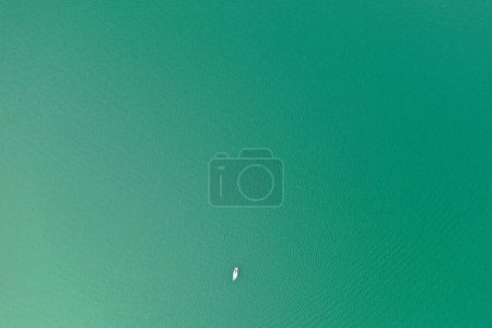 Photo for A single sailboat rests on the peaceful waters of a Slovenian lake, presenting a stunning contrast of solitude against the vastness of nature, as seen from a drone's eye view. - Royalty Free Image
