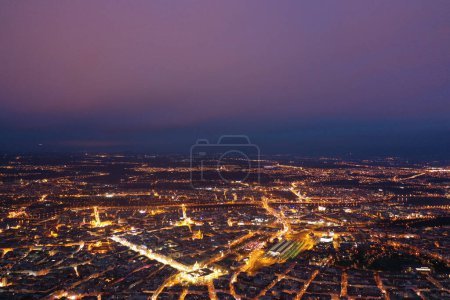 Photo for As dusk sets in, this aerial image from a drone captures the sprawling cityscape of Prague, with the last light of day casting a soft glow over the city. The intricate layout of the streets, buildings, and the Vltava River can be seen in the fading l - Royalty Free Image
