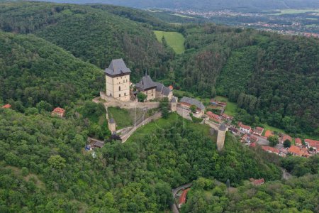 Photo for The aerial image captures the timeless elegance of a historic Czech Karlstejn castle, nestled within the embrace of lush greenery, standing as a guardian of history and architectural marvel amid the forest's whispers. - Royalty Free Image