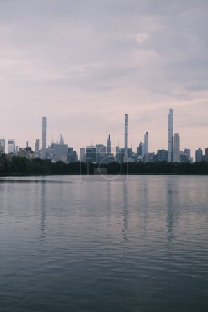 Photo for As dusk settles over New York, the calm waters offer a reflective surface for the city's skyline, creating a stunning and meditative juxtaposition between the bustling city and the tranquil water. - Royalty Free Image