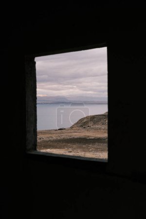 Téléchargez les photos : Peering through an ancient window frame in Jordan, one is treated to a mesmerizing view of the Dead Sea, its tranquil waters bordered by the rugged landscape. This framed perspective offers a unique vantage point, blending historical architecture wit - en image libre de droit