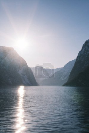 Photo for The sunset casts a brilliant array of lights over the Norwegian fjord, creating a radiant path on the water's surface and highlighting the sheer cliff faces, embodying the peaceful end to a day in Norway's majestic landscapes. - Royalty Free Image