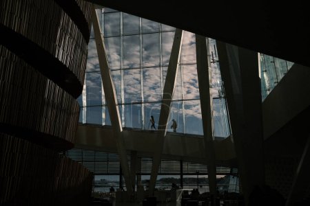Photo for This dramatic image from inside the Oslo Opera House captures human silhouettes against the vast windows overlooking the fjord, creating a striking visual narrative of culture and architecture in Norway. - Royalty Free Image
