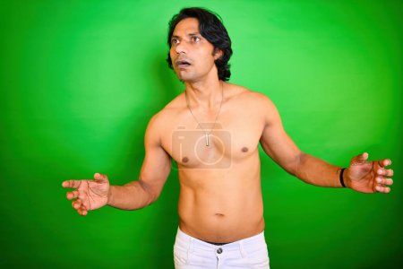 Surprised shirtless man fearful expression, Shocked young man, Portrait of a person with shocking face, Indian, Afraid men pose, Standing against a green background, Fear and exited facial look, 30s.