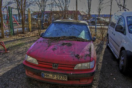 Téléchargez les photos : Vieille voiture abandonnée.La voiture rouge est debout à un seul endroit depuis des années. Les roues sont plates, le corps est pourri, l'apparence est déprimante triste. - en image libre de droit