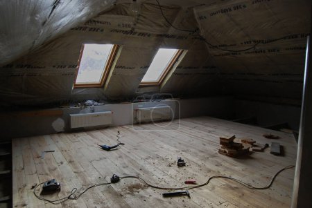 Photo for Construction of an attic with two windows.Insulating the room and laying floorboards. - Royalty Free Image