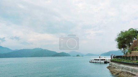 scenic photo of boat on lake with mountain and sky background