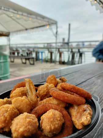 Eine Schüssel gebratener Snack besteht aus Chicken Wing, Zwiebelring und Chicken Karaage mit Blick auf das Meer Café Hintergrund