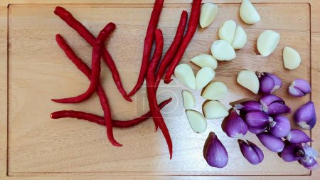 Top view of red chilies, garlic and shallots on a cutting board
