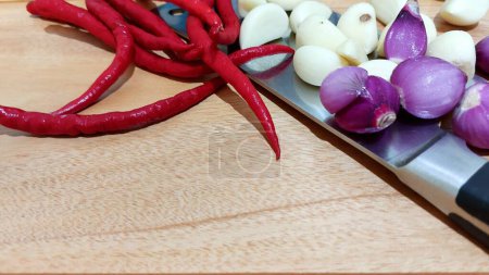 Vista superior de chiles rojos, ajo y chalotes en una tabla de cortar