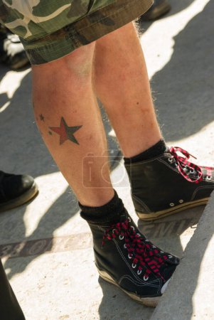 Téléchargez les photos : Tatouage étoile sur la cuisse de jeune homme en short de camouflage - en image libre de droit