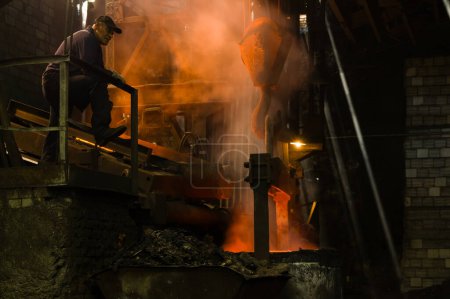 Téléchargez les photos : Métallurgiste coulant le métal fondu chaud hors du four - en image libre de droit