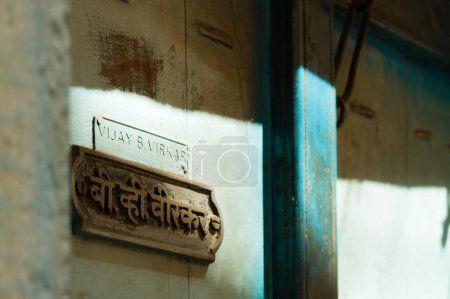Foto de Puerta azul de madera con nombre escrito en escritura devanagari y en escritura latina en Pune, India - Imagen libre de derechos
