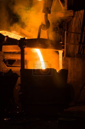 Téléchargez les photos : Métallurgiste coulant le métal fondu chaud hors du four - en image libre de droit