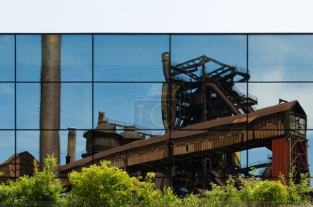 Téléchargez les photos : Reflet de bâtiments industriels abandonnés dans une façade en verre d'un bâtiment urbain moderne - en image libre de droit