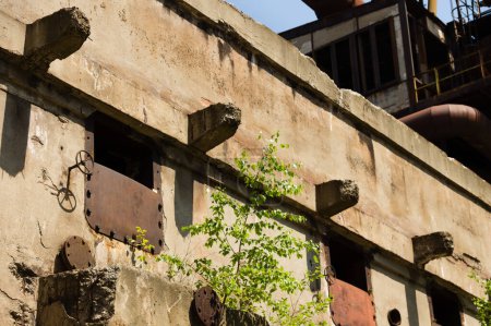 Téléchargez les photos : Ancien bâtiment en béton avec portes métalliques dans une zone industrielle abandonnée - en image libre de droit