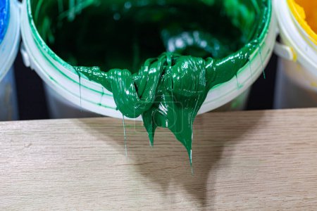 Photo for .Green paint dripping from white barrel..plastisol ink is used for printing on fabrics because it is durable,. easily cured and can be stretched without cracking or becoming distorted.. - Royalty Free Image
