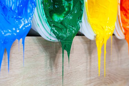 Green yellow and orange paints are dripping from white barrel