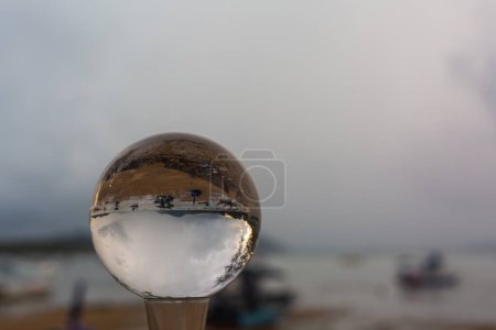 Téléchargez les photos : Coucher de soleil vue du lever du soleil à l'intérieur boule de cristal sphère de cristal révèle le coucher de soleil paysage marin avec perspective sphérique sur la plage de l'île de Phuket. La vue dans une boule de cristal ne ressemble à aucune autre. - en image libre de droit