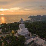 aerial view Phuket big Buddha in beautiful sunset.amazing sun shines through the yellow clouds impact on golden sea surfaceThe beauty of the statue fits perfectly with the charming nature.
