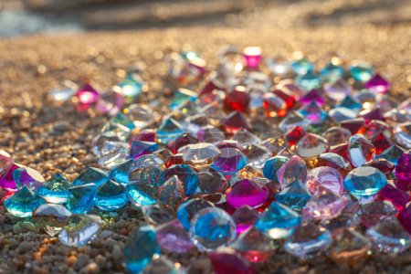 Téléchargez les photos : Diamants colorés éparpillés sur la plage Le soleil brillait sur les facettes des pierres précieuses - en image libre de droit