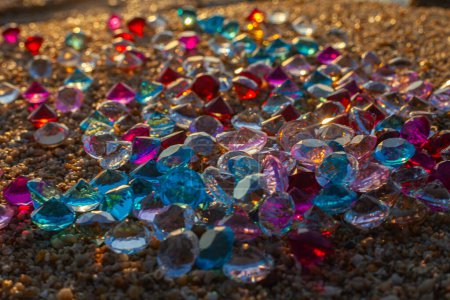 Téléchargez les photos : Diamants colorés éparpillés sur la plage Le soleil brillait sur les facettes des pierres précieuses - en image libre de droit