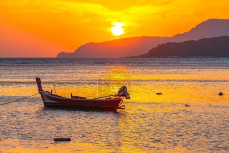 Photo for Amazing yellow sky of sunrise above the island, fishing boat parking on the golden sea. - Royalty Free Image