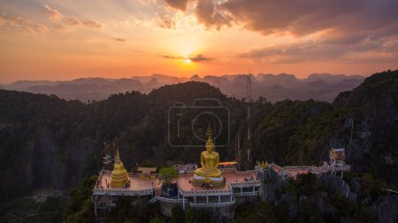 Téléchargez les photos : Vue aérienne du Bouddha doré construit au sommet d'une haute montagne. Paysage de ciel magnifique au coucher du soleil au-dessus du sommet de la colline. Paysage nuageux coloré. - en image libre de droit