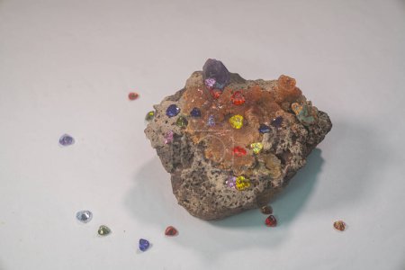 Foto de Diamantes coloridos en forma de corazón engastados sobre una piedra preciosa de ópalo en bruto sobre un fondo blanco - Imagen libre de derechos