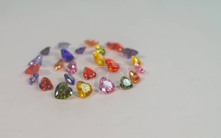 Photo for Beautiful multi-colored heart-shaped diamonds set in a circle.Heart-shaped diamonds in various colors are set on white floor.The sparkling light of diamonds looks charming and beautiful. - Royalty Free Image