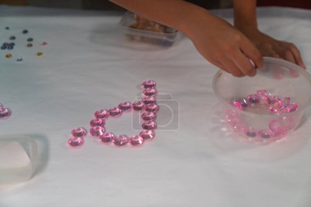 Foto de .El niño utiliza cuidadosamente los diamantes para hacer letras en el estudio.. video de alta calidad 4K. juego con gemas de colores es una gran manera para que los niños aprendan. .. fondo de gemas de colores - Imagen libre de derechos