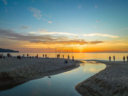 Foto de Vista aérea del sinuoso canal en la playa de arena.Los turistas observan la puesta de sol junto a un pequeño canal en una playa de arena.hermoso reflejo del cielo en el canal.bubble olas y el paisaje de arena clara. - Imagen libre de derechos