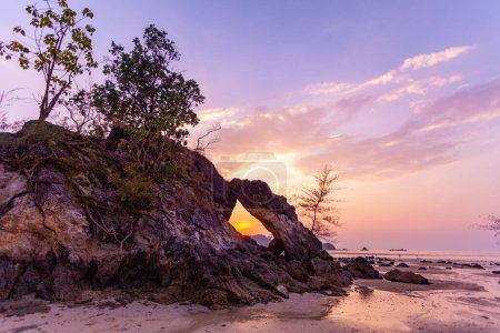 Téléchargez les photos : Incroyable Le soleil du soir brillait à travers le grand trou de roche et scintillait magnifiquement. - en image libre de droit