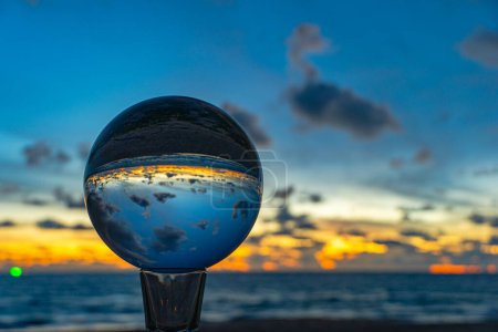 Ce laps de temps a été capturé à l'aide d'une boule de cristal pour capturer le ciel coloré. magnifique coucher de soleil à la mer au crépuscule.