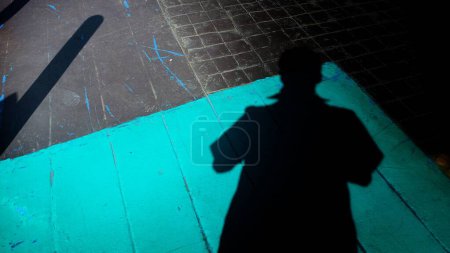Foto de Una persona de pie en una acera con una sombra de una persona - Imagen libre de derechos