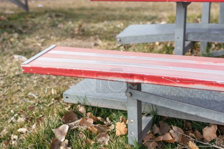 Téléchargez les photos : Un gros plan des gradins en métal rouge et blanc sur un terrain d'athlétisme. - en image libre de droit