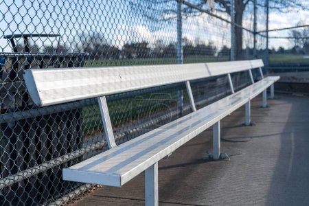 Foto de Un banco de aluminio vacío en un campo de béisbol en un parque público. - Imagen libre de derechos