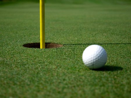 Téléchargez les photos : Boule de golf sur un green à côté d'un trou - en image libre de droit