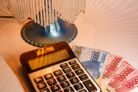 Foto de Billetes y calculadora de rupia indonesia con iluminación amarilla de lámparas decorativas - Imagen libre de derechos