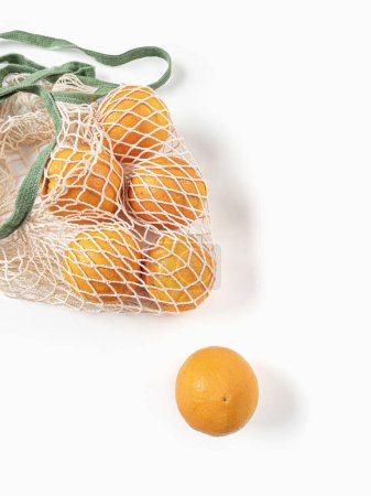 Fresh unpeeled oranges placed in reusable white mesh bag. High quality photo