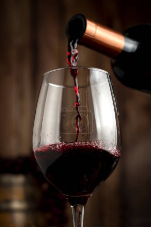 Téléchargez les photos : Verre de vin rouge avec une bouteille de vin sur une table de natures mortes avec des raisins en bois tonneau bouchons ouvreur et verre de vin servant sur des planches en bois. - en image libre de droit
