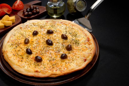 Téléchargez les photos : Variété de pizzas aux légumes champignons fromages différents olives tomate roquette origan pepperoni sur planche de bois et ingrédients sur table noire - en image libre de droit