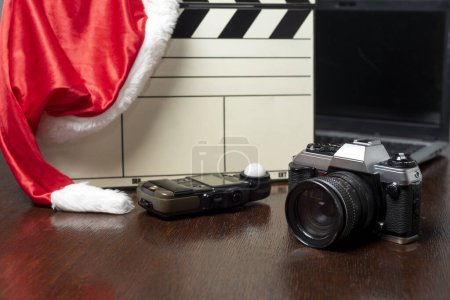 Téléchargez les photos : Appareils photo, planches à clins d'ordinateur et objets photographiques décorés d'un chapeau de Noël sur bois - en image libre de droit