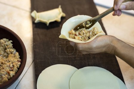 Téléchargez les photos : Processus de fabrication crue empanadas maison avec la pâte et le remplissage avec des mains assembler et remplir les empanadas avec des légumes viande poulet jambon et fromage et faire la répulsion - en image libre de droit