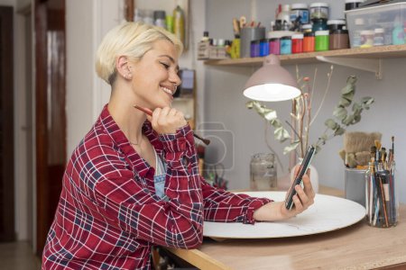 Téléchargez les photos : Jeune artiste peintre femme créer et peindre à son espace de travail avec les mains peintes heureux avec son style de vie - en image libre de droit