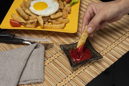 Téléchargez les photos : Assiette avec frites et oeufs frits avec garnitures et ingrédients avec pommes de terre à tartiner à la main avec oeuf et sauce - en image libre de droit