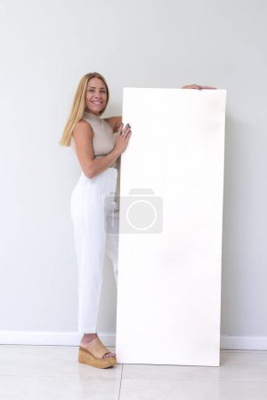 Téléchargez les photos : Joyeux jeune femme adulte avec de grandes peintures et cadres de peinture dans les mains avec toile vierge - en image libre de droit
