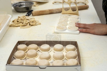 Téléchargez les photos : Fabrication de pâtes maison mains remplissant les sorrentinos et étirant la pâte dans des moules avec le remplissage dans une cuisine - en image libre de droit