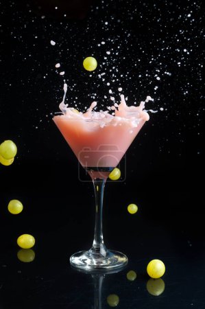 Téléchargez les photos : Verres à cocktail et verres coups de feu et boissons sur le bar avec shaker et fruits frais oranges fraises bananes raisins citron avec de l'alcool jus de fruits faire éclabousser de liquide volant dans l'air - en image libre de droit