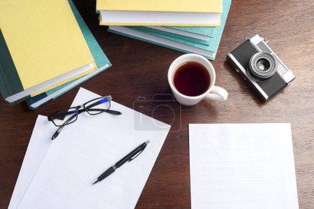 Téléchargez les photos : Bureau avec livres ordinateur tasse de thé et café cahiers stylo et cartes appareils photo de travail de la maison et l'organisation d'un concept de style de vie voyage - en image libre de droit